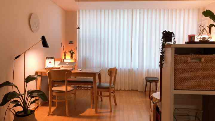 White and natural tone studio apartment featuring multifunctional dining table and warm lighting with cozy atmosphere