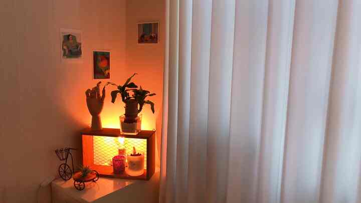 Minimalistic corner space featuring white curtains and wood-tone corner storage with decorative objets