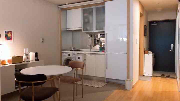 ホワイトとゴールドのトーンでまとめられたコンパクトなキッチン、円形テーブルとゴールドチェア、清潔感のあるインテリアが印象的な雰囲気のある空間