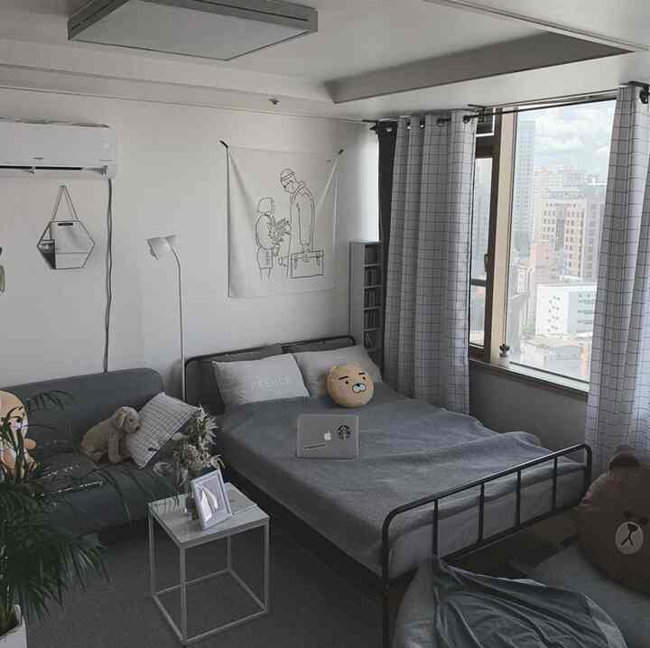 Gray and white toned studio bedroom featuring a bed, sofa, and checkered curtains in a natural modern style