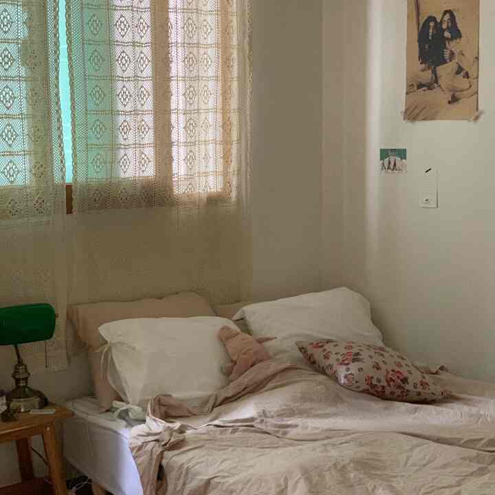 Beige and white toned bedroom featuring vintage style curtains and poster with a cozy atmosphere