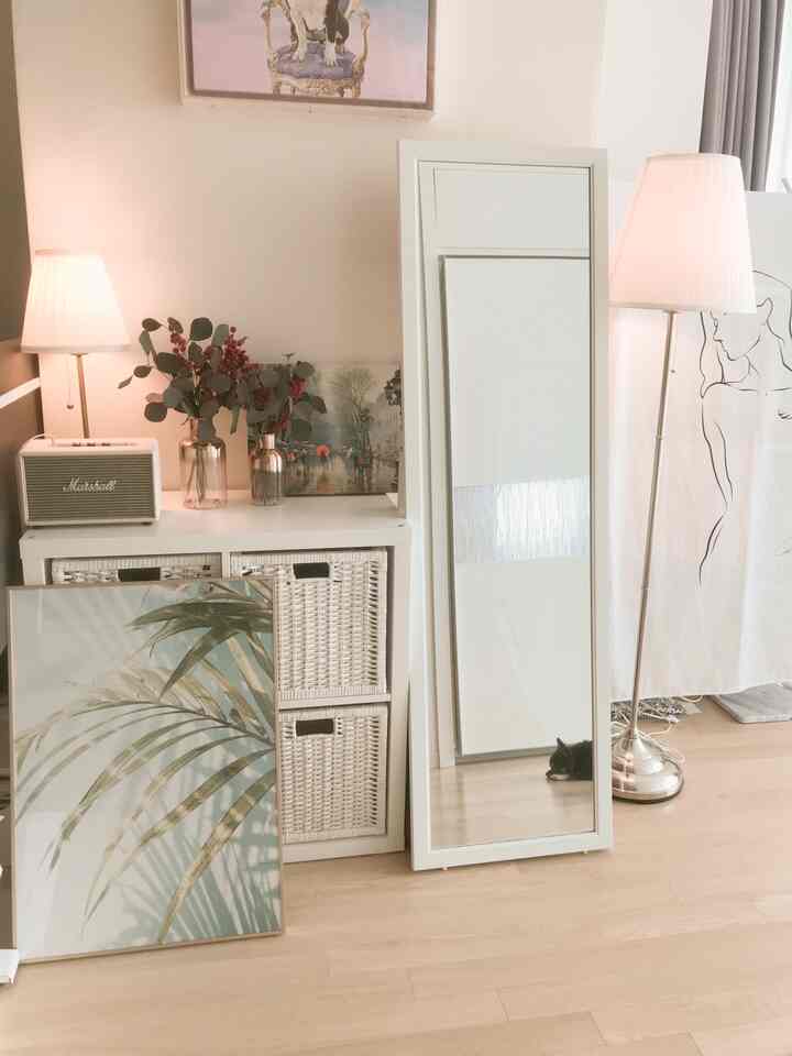 ホワイトとブラウンの色調のリビング、チェストと全身鏡、フロアランプが配置された雰囲気のあるインテリア