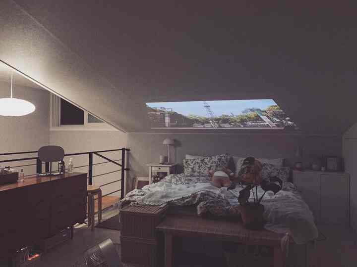 White and brown toned loft bedroom featuring bed and rattan furniture with cozy atmosphere