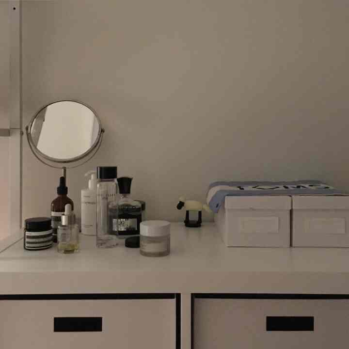 ホワイトトーンのワンルーム化粧台、収納ボックスと小さな鏡が整頓されたシンプルな空間