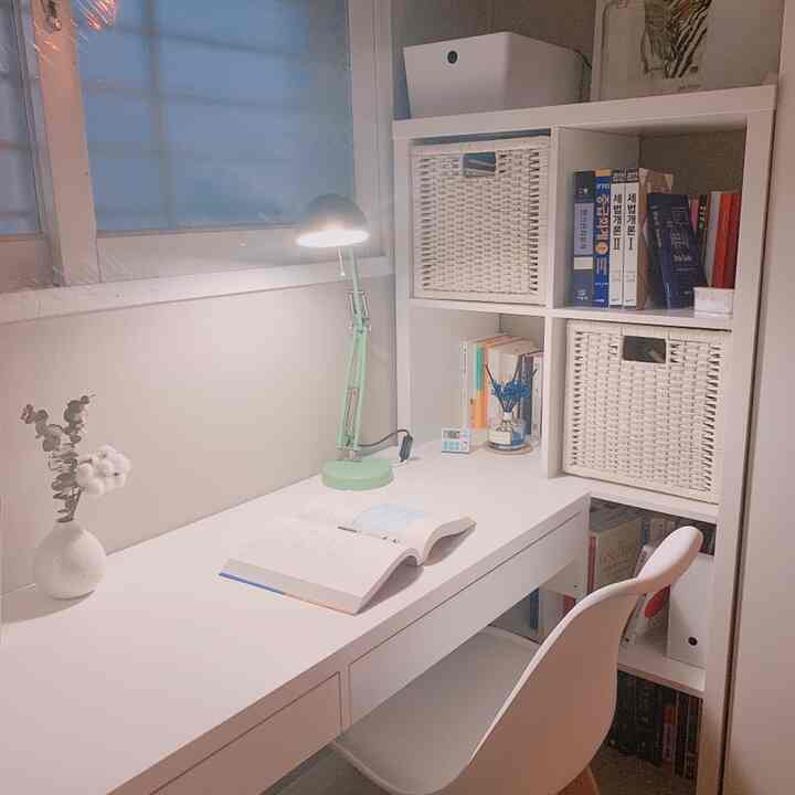 Compact white-toned study featuring a desk, bookshelf, and mint green desk lamp creating a focused ambiance