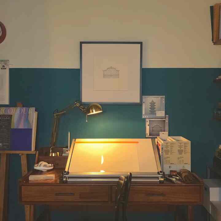 Workspace with wood tones and deep blue wall, featuring a wooden desk and vintage lamp creating a cozy atmosphere