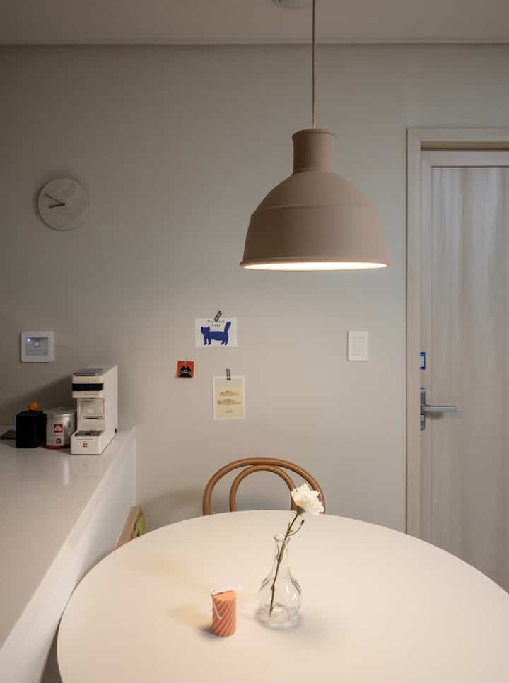 White and beige kitchen space featuring a round table and pendant light with a simple and cozy atmosphere