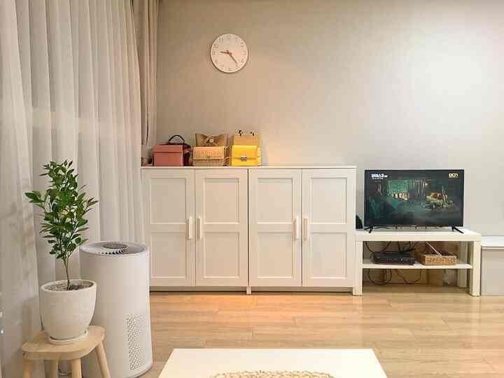 Bright white walls and furniture define this studio living room featuring an IKEA storage cabinet and TV stand for neat organization