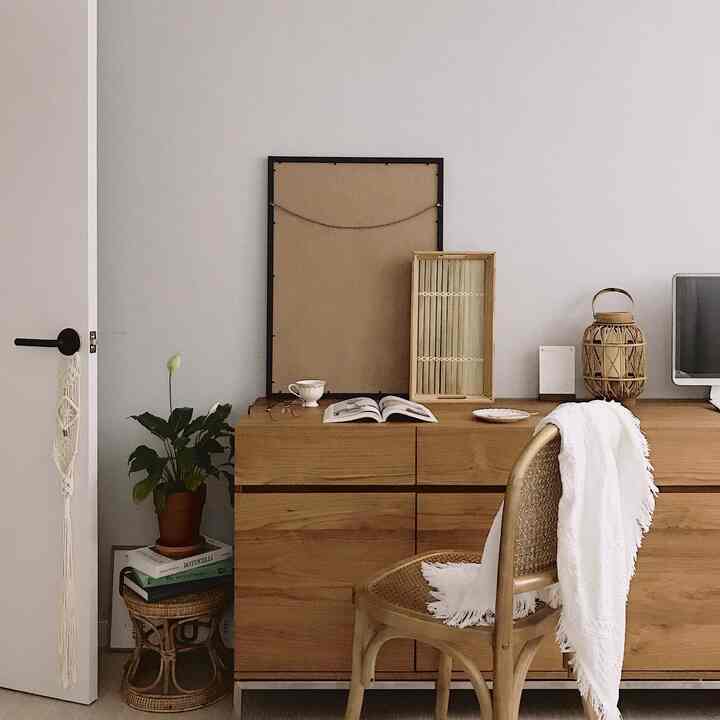 ナチュラルなトーンの寝室の一角、チーク材のサイドボードとラタンチェアが配置された温かみのある空間
