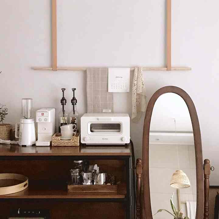 Natural beige and wood tone home cafe space featuring white appliances and a wooden framed mirror with a simple aesthetic