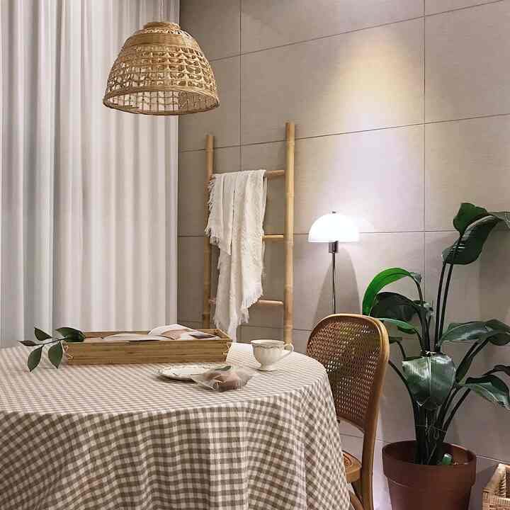 A beige and natural toned dining room featuring bamboo lighting and rattan chair with a cozy, natural atmosphere