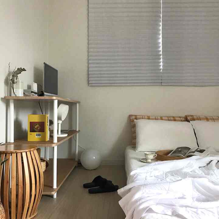White and beige toned bedroom featuring a wood stool and desk, creating a simple and natural atmosphere