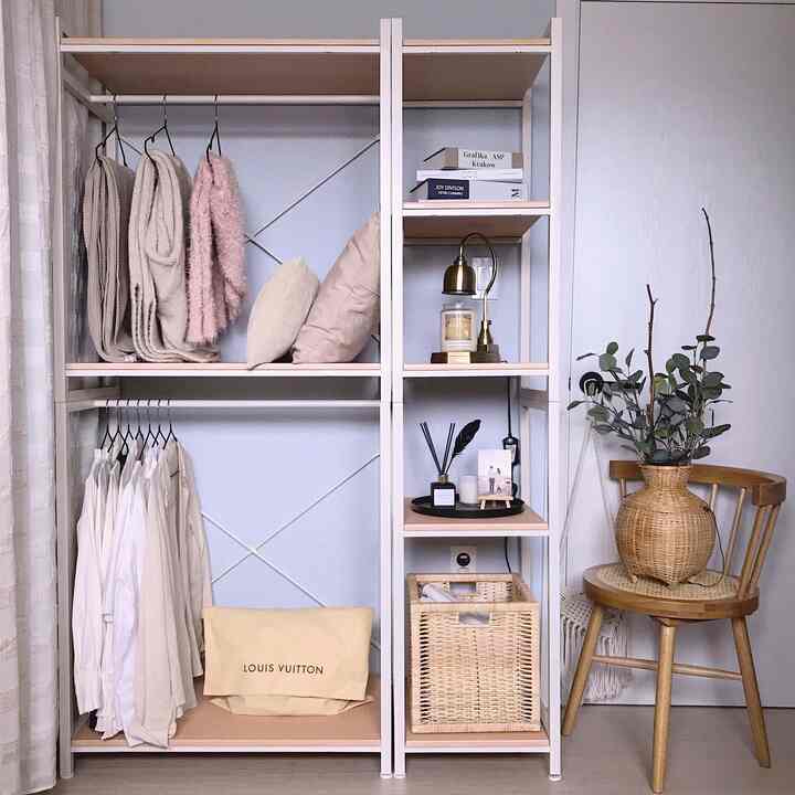 Walk-in closet space in bright beige and wood tones featuring white shelves, a beige chair, and various decor items creating a cozy atmosphere