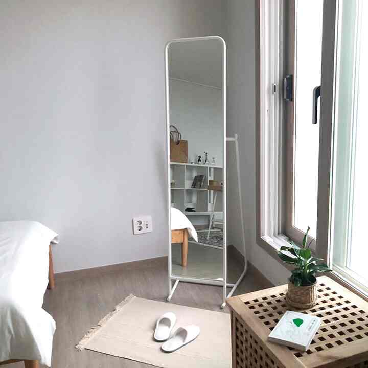 Natural tone entrance space featuring a full-length mirror and wooden storage cabinet with a clean atmosphere