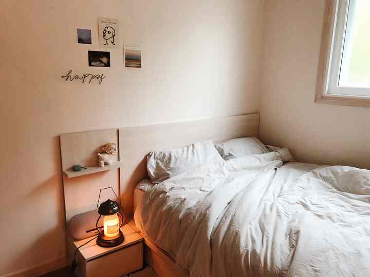 Beige-tone bedroom featuring a bed and nightstand with candle creating a cozy and warm atmosphere