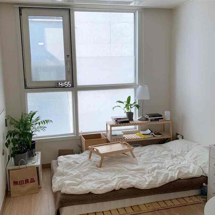 A natural modern 6-pyeong studio bedroom featuring white and wood tones, low bed with wooden shelves and a digital LED clock