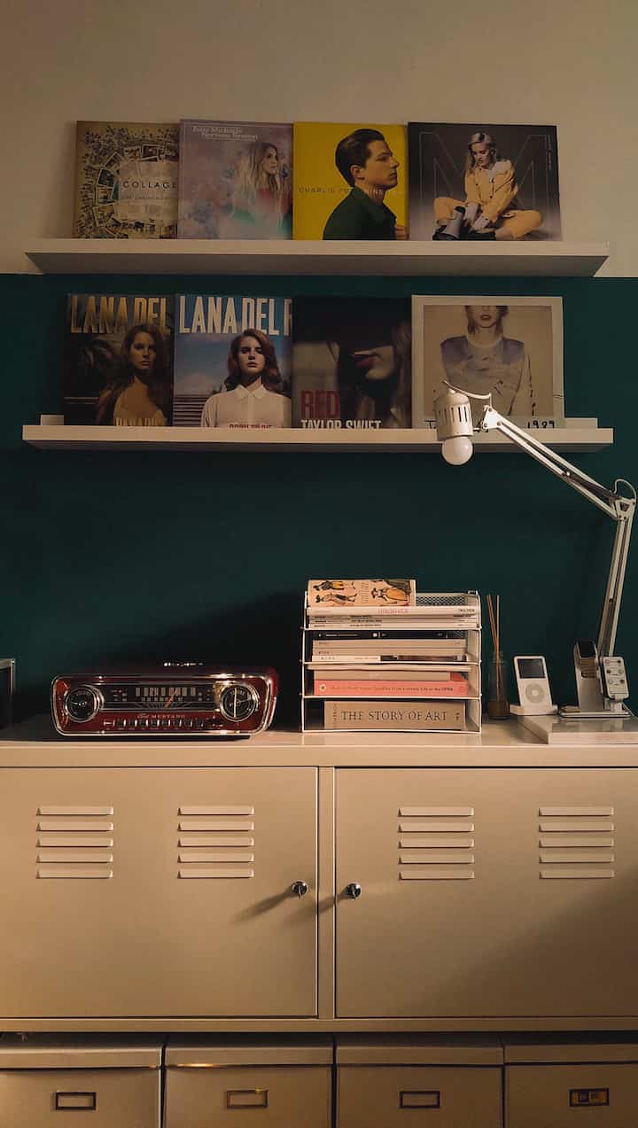 ダークグリーンの壁とベージュの金属キャビネットがあるレトロ風のLPと本の収納スペース