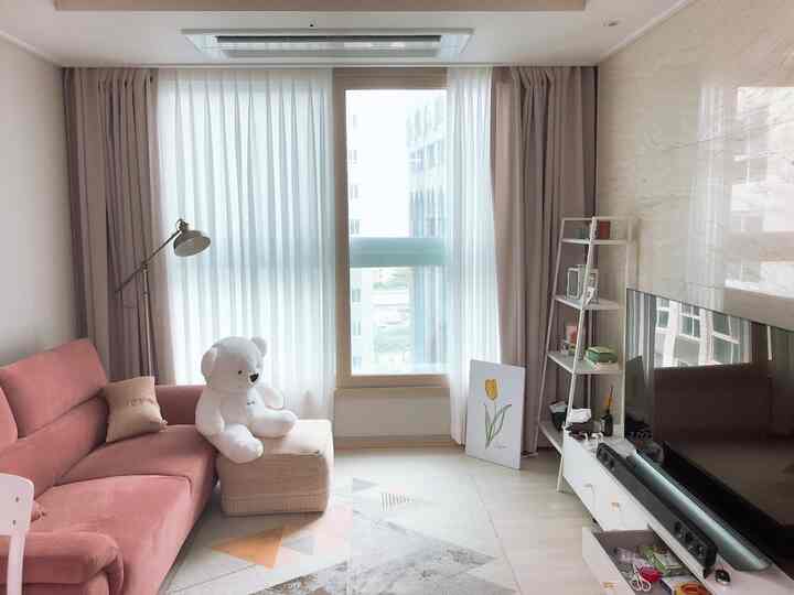 Beige and pink toned living room featuring curtains and sofa, creating a cozy and bright newlywed home space
