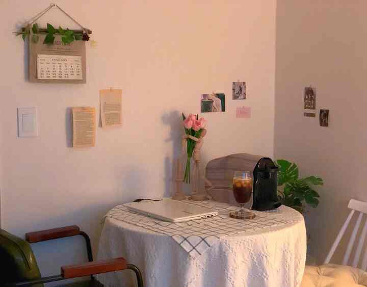 Soft white and natural toned dining room featuring a table with flowers and coffee machine, creating a cozy warm atmosphere