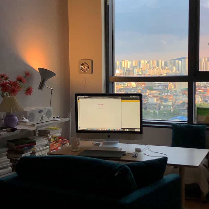 ホワイトとブルーのトーンのワンルームホームオフィス、Apple iMacとデスク、本棚が配置されたモダンな雰囲気のインテリア