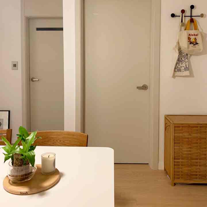 Natural wood tone kitchen and entrance space featuring a dining table with a small plant, creating a cozy atmosphere
