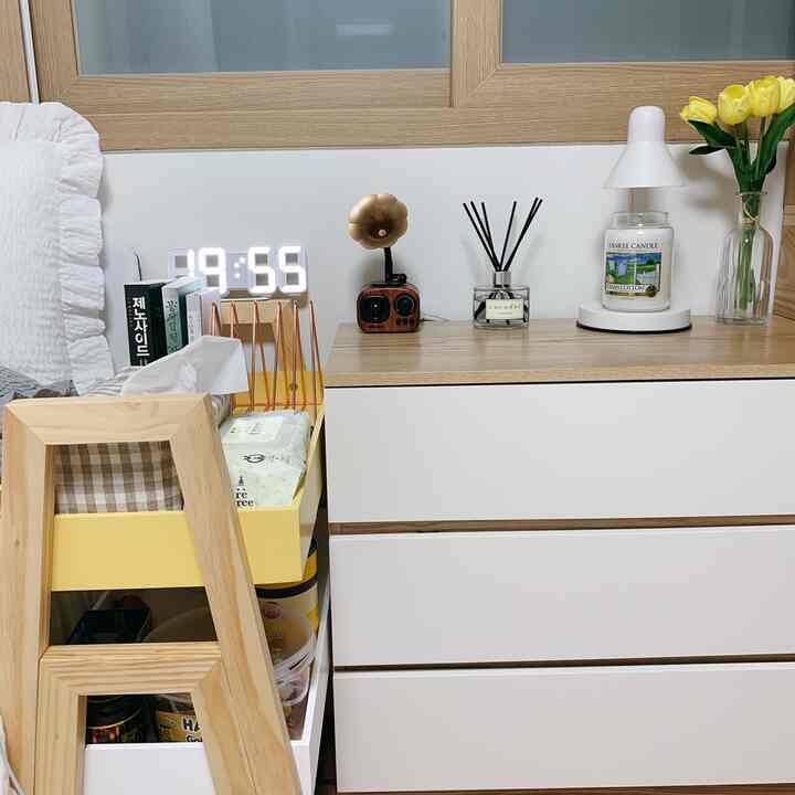 White and wood tone bedroom nightstand area featuring LED clock, candle, and tray with cozy atmosphere