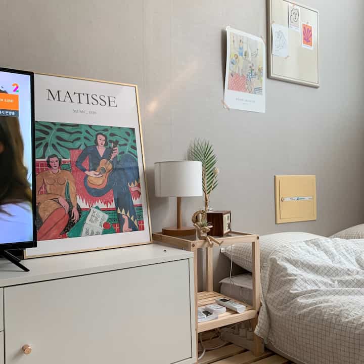 Natural color tone bedroom featuring wooden bed frame, art picture frame, and cozy lamp setup