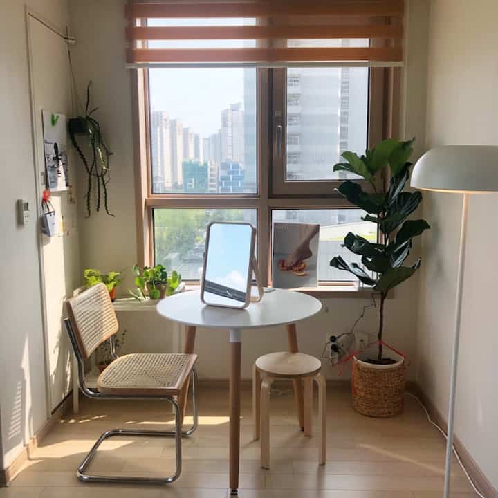 Dining room with white and wood tones featuring a rattan chair and white round table in a natural plant interior setting