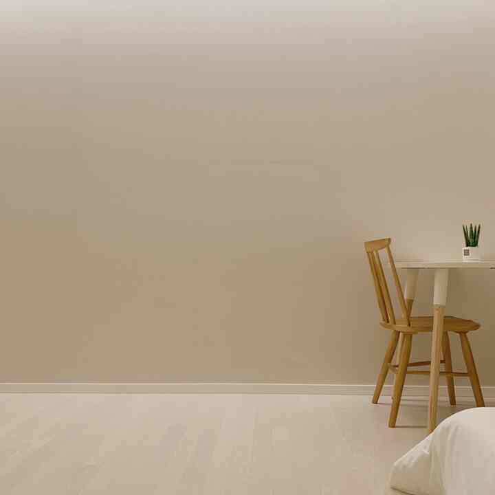 Beige-walled minimal studio apartment featuring wood tone dining table and chair