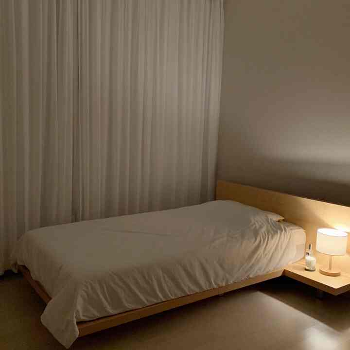 White and wood-toned bedroom featuring a simple bed and nightstand creating a cozy atmosphere