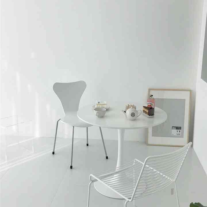 White-toned small dining space featuring a round table and two dining chairs, with modern and simple interior design
