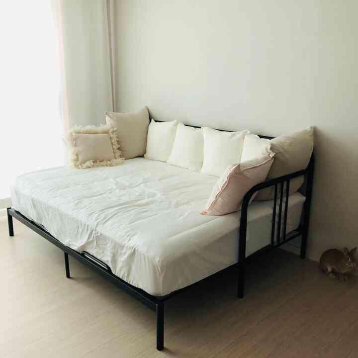 White and black toned bedroom space featuring a black sofa bed with cushions showcasing a simple atmosphere