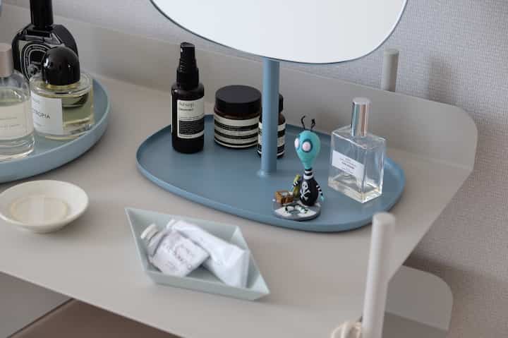 Natural color vanity shelf featuring neatly arranged cosmetics and accessories on trays in a simple space