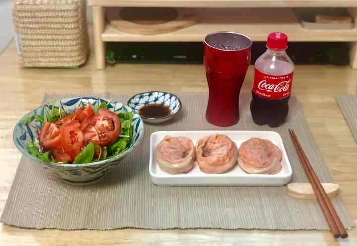 ライトブラウンのワンルームのダイニングテーブルに餃子、サラダ、ドリンクが配置された落ち着いたひとりごはん空間