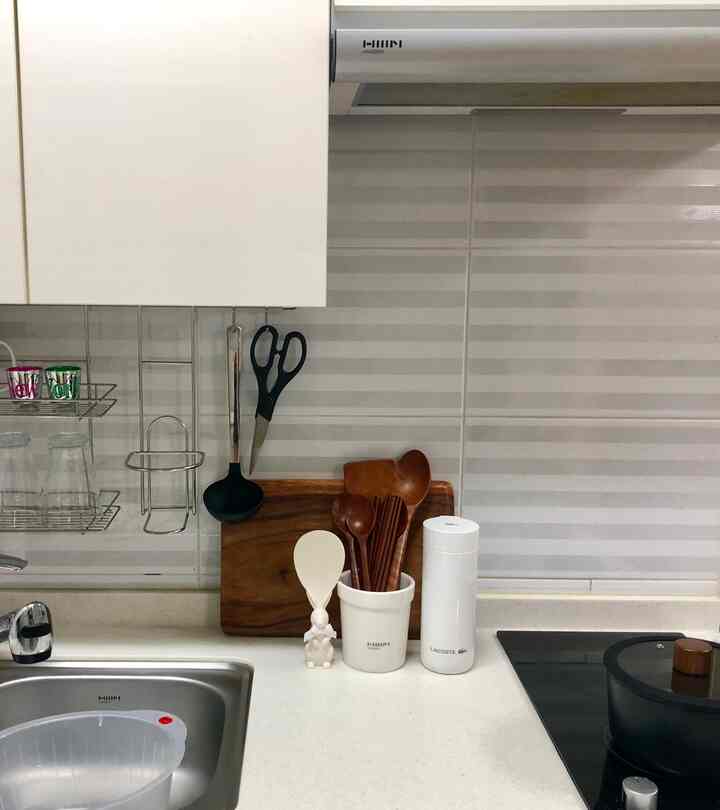 アイボリー色調の小さなワンルームキッチン、整然と配置された調理器具と鍋がある雰囲気のあるインテリア