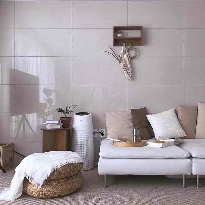 ベージュ色調のリビング、白いソファとラタンのスツールが配置された落ち着いた空間