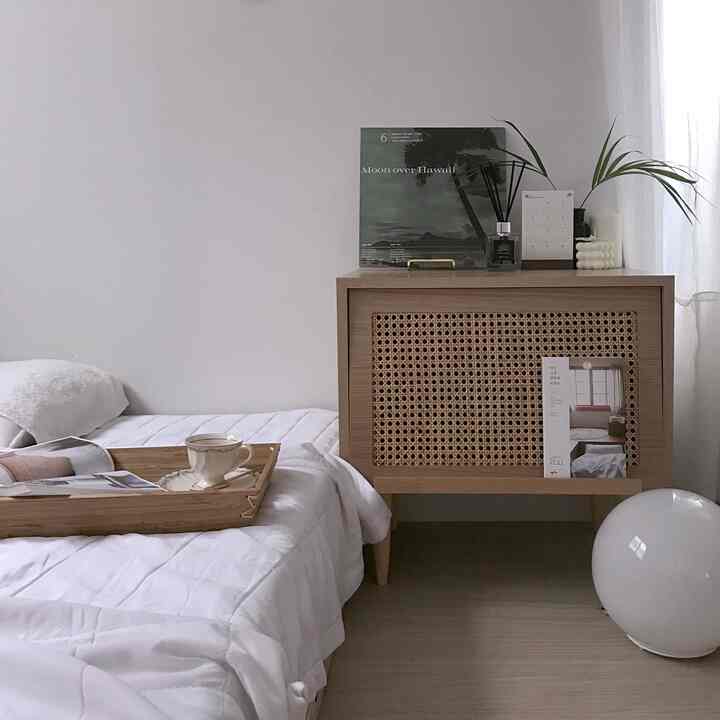 White and wood-toned bedroom featuring a nightstand with plants and books creating a cozy atmosphere