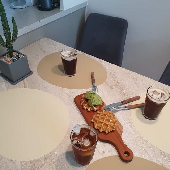 Beige and wood-toned home cafe dining table featuring iced Americanos and waffles in a cozy setting