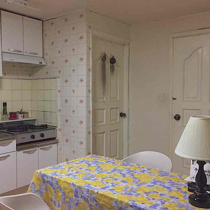 Retro style kitchen featuring white cabinetry and walls, with a yellow and blue floral tablecloth on the dining table
