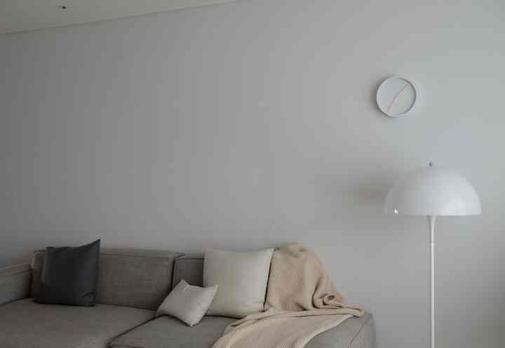 Simple modern living room with gray sofa and white floor lamp, arranged in a neat and minimal style