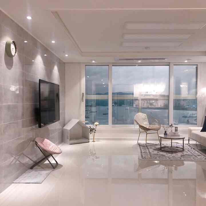 Gray and white toned living room featuring large windows, sofa, and side table with a clean and modern atmosphere