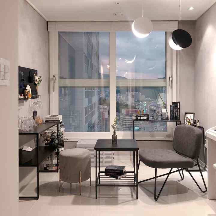 A compact living room in calm gray and black tones featuring modern metal furniture and a pegboard shelf in a minimalist setting