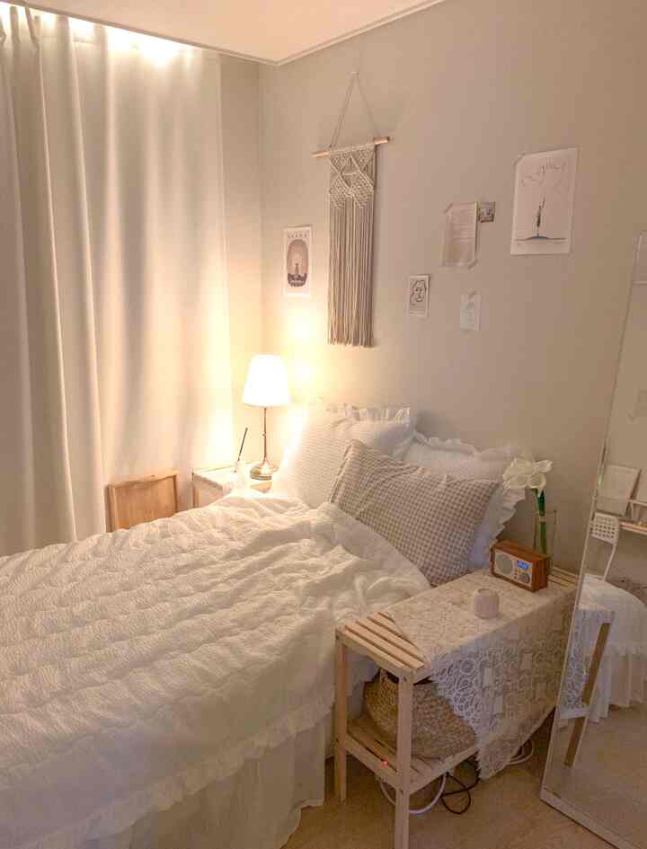 A white and beige toned bedroom featuring clean bedding, small furniture, and a cozy, calm atmosphere