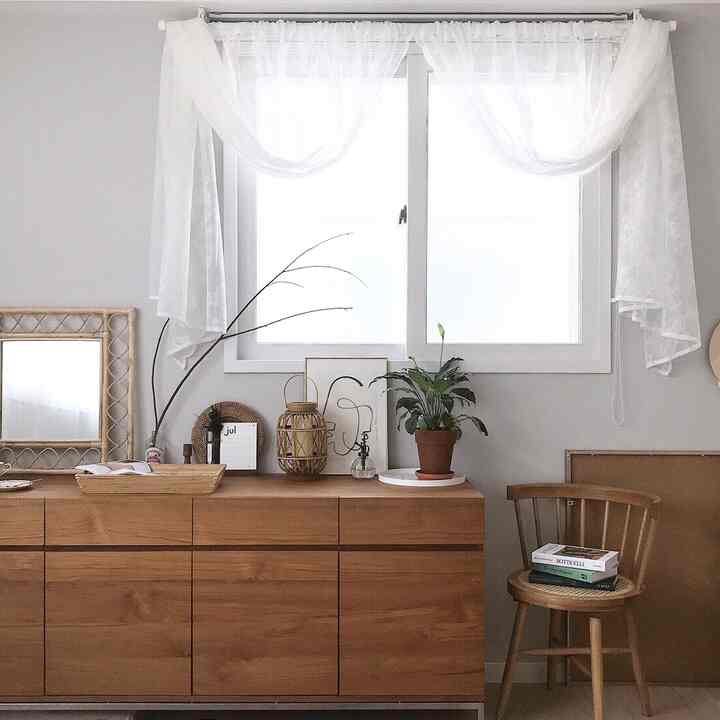 White and wood-toned dining room featuring sideboard and chair with plants and picture frames for a cozy atmosphere