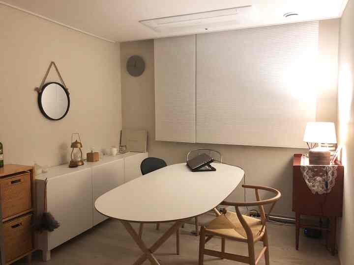 ベージュ色の壁と白いテーブルがあるコンパクトな二人暮らし向けリビング、ナチュラルな家具とシンプルなインテリア