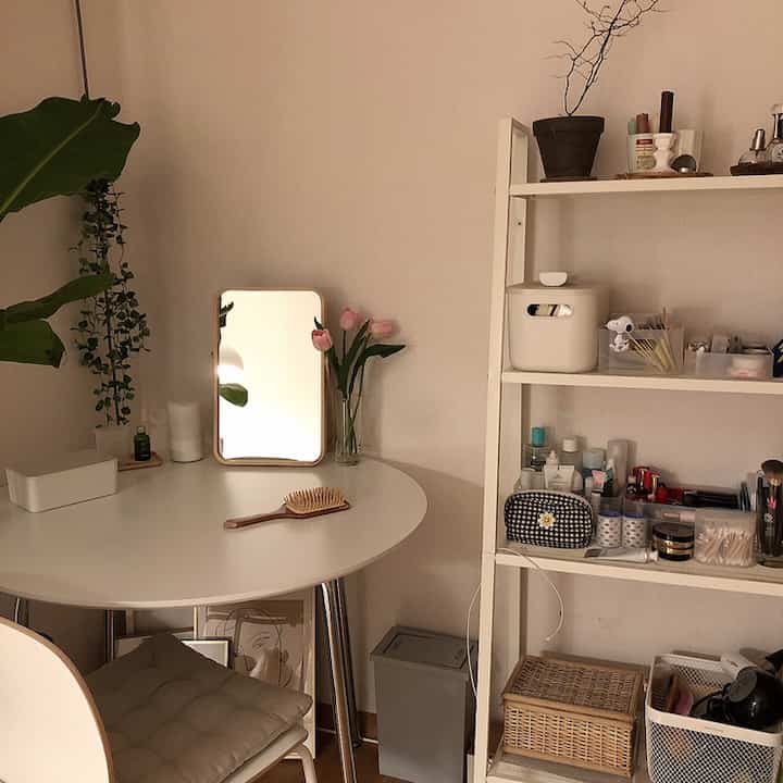 A cozy, natural space with white tones featuring a round table and shelves in a living area