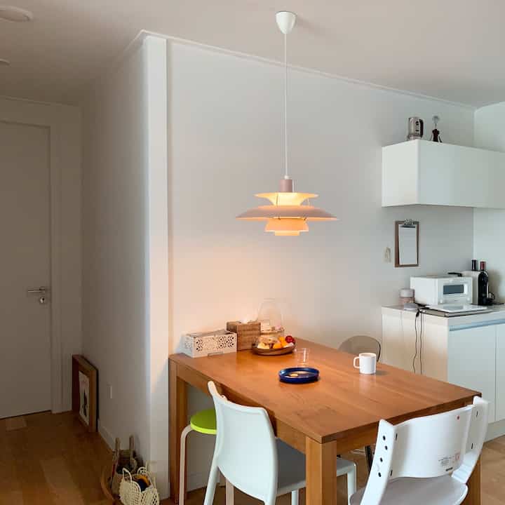 White and brown wood tone dining room featuring a modern natural style dining table and pendant light creating a cozy atmosphere