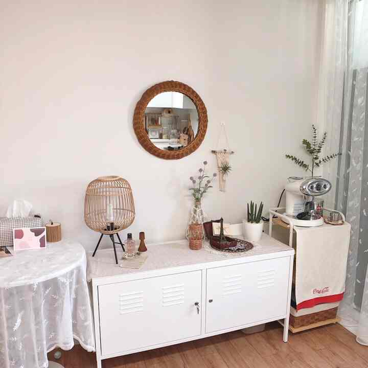 白とベージュの木目調が調和したワンルームのおうちカフェ空間、金属製キャビネットとラタンの鏡が配置された雰囲気のあるインテリア