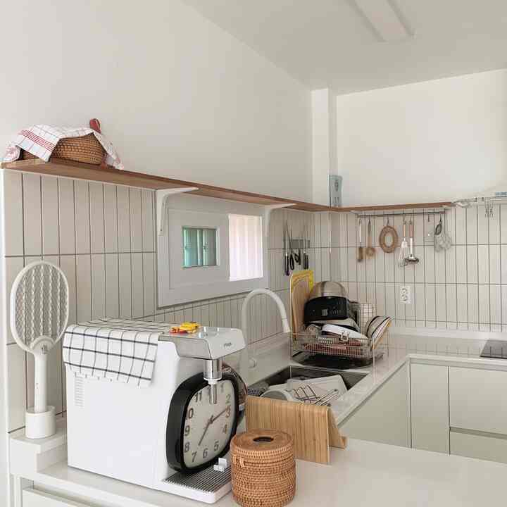 Compact kitchen with white and natural wood tones, featuring smart storage ideas and a clean, organized atmosphere