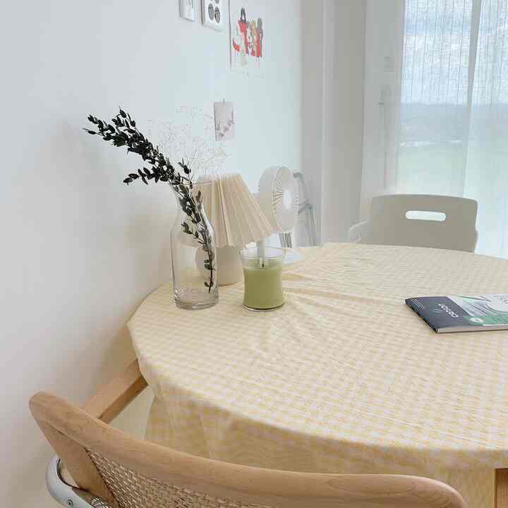 Bright white-toned living room dining space featuring a yellow round tablecloth-covered dining table